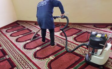 Cleaner vacuuming a carpet with a vacuum cleaner in an office space