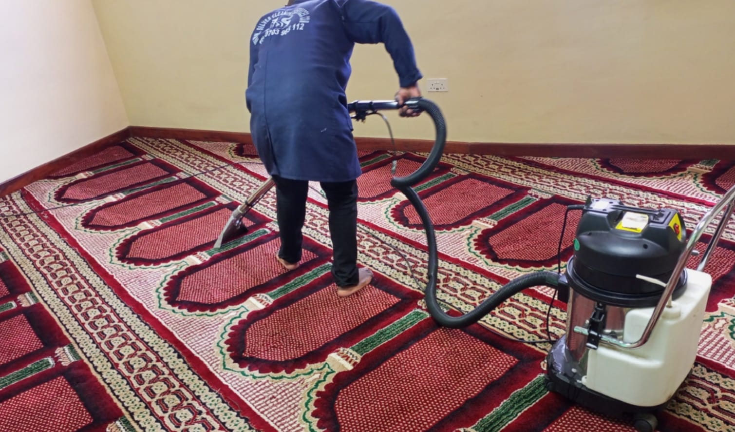 Cleaner vacuuming a carpet with a vacuum cleaner in an office space